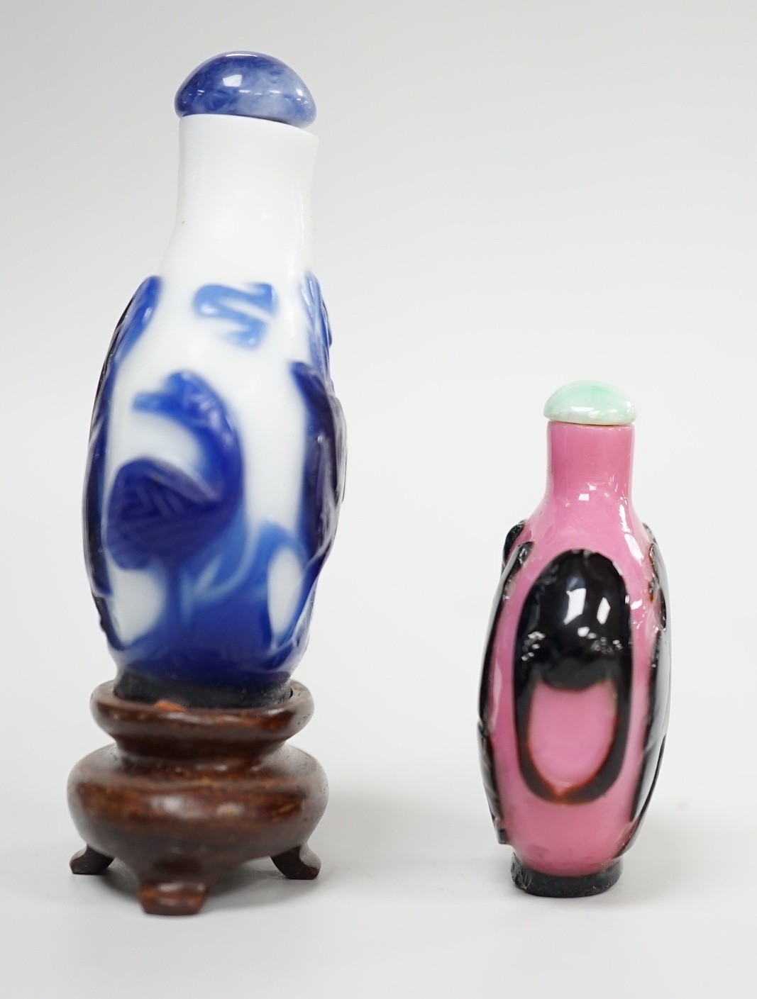 Two Chinese overlay glass snuff bottles, the black and pink bottle in imitation of shadow agate, 18th century, decorated with an eagle and the moon the reverse with a dog tied to a chain, 4.3cm, the blue and white exampl